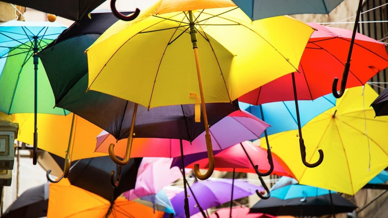 Underneath different colour umbrellas, hanging in the sky